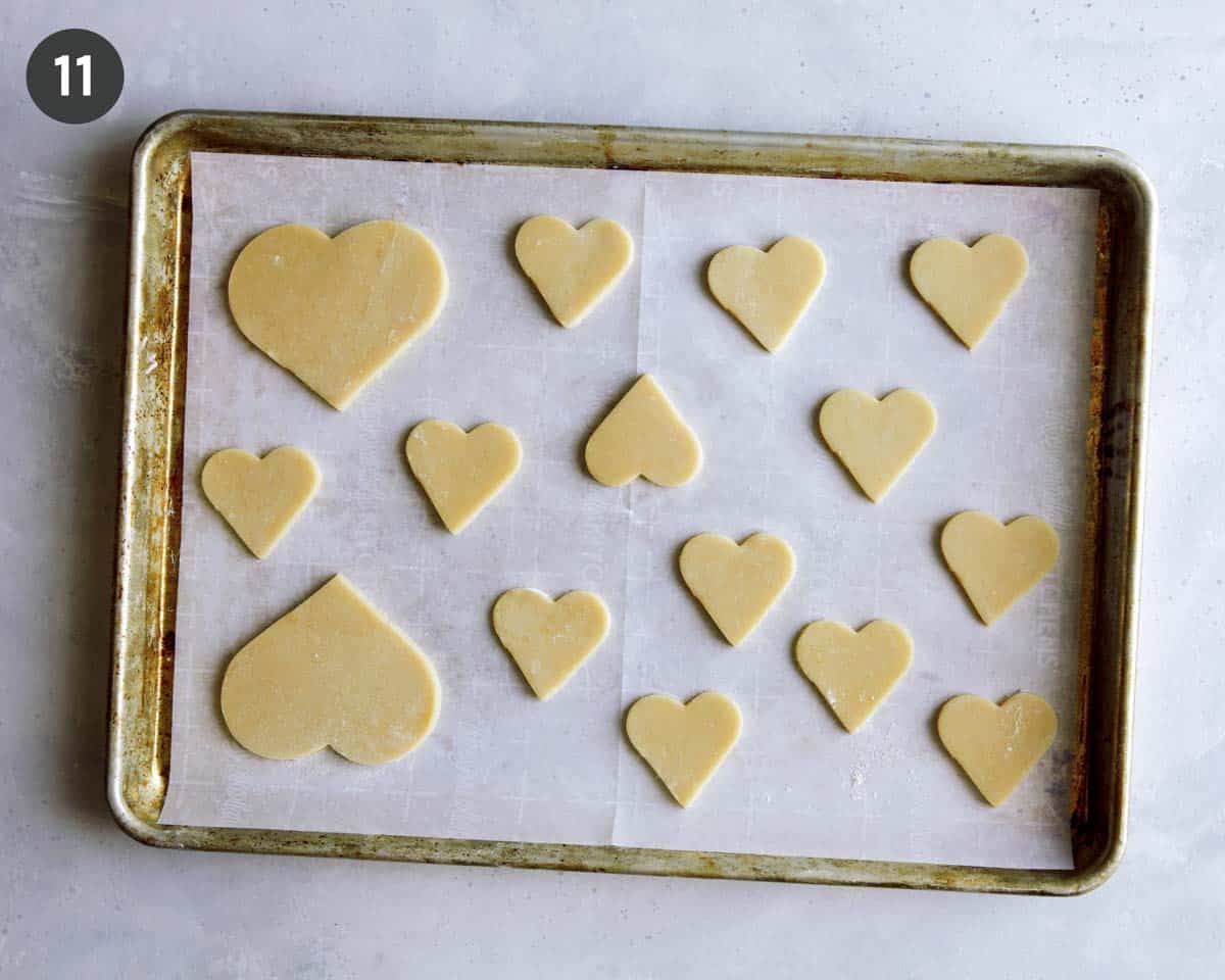 Heart cookies laid out on a baking sheet ready to be baked.