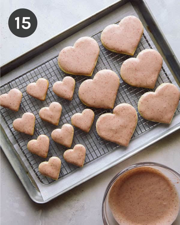 Cookies dipped in frosting then resting on a cooling rack.