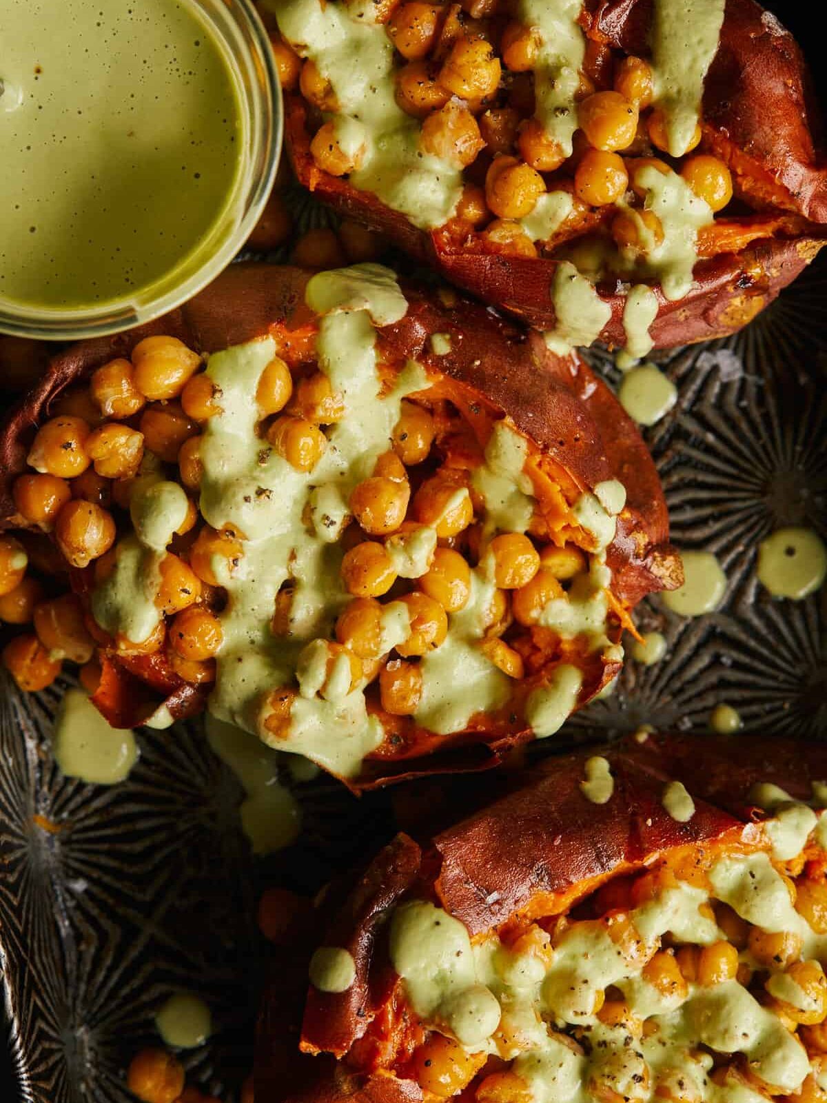 A close up of roasted chickpea stuffed sweet potatoes with cilantro garlic cashew sauce.