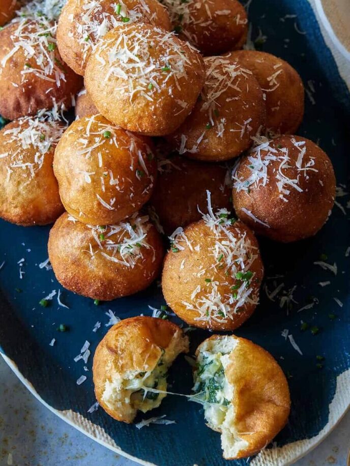A platter of spinach and artichoke stuffed beignets and a serving on small plates.