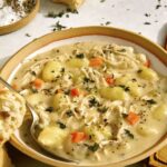 Chicken and gnocchi in a bowl with bread.