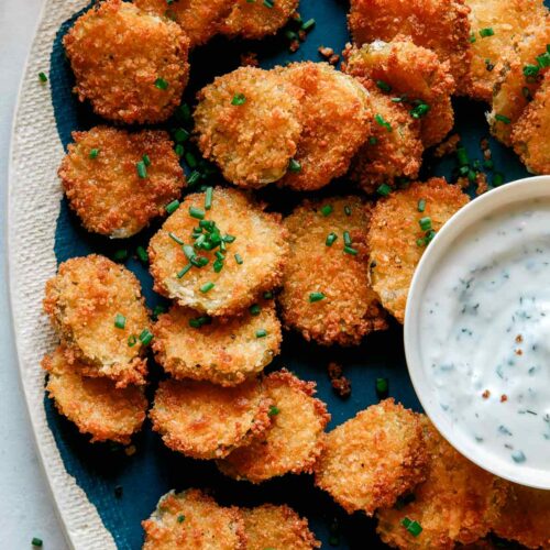 Fried pickle chips on a platter with ranch dressing.