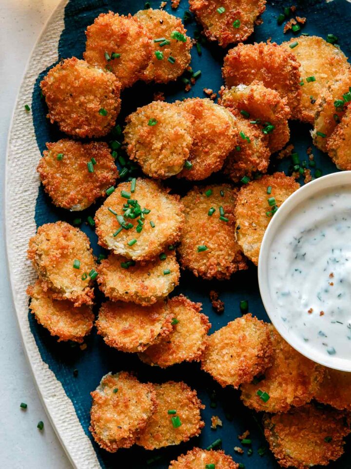 Fried pickle chips on a platter with ranch dressing.