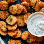 Close up on Fried Pickle Chips on a platter with ranch dressing.