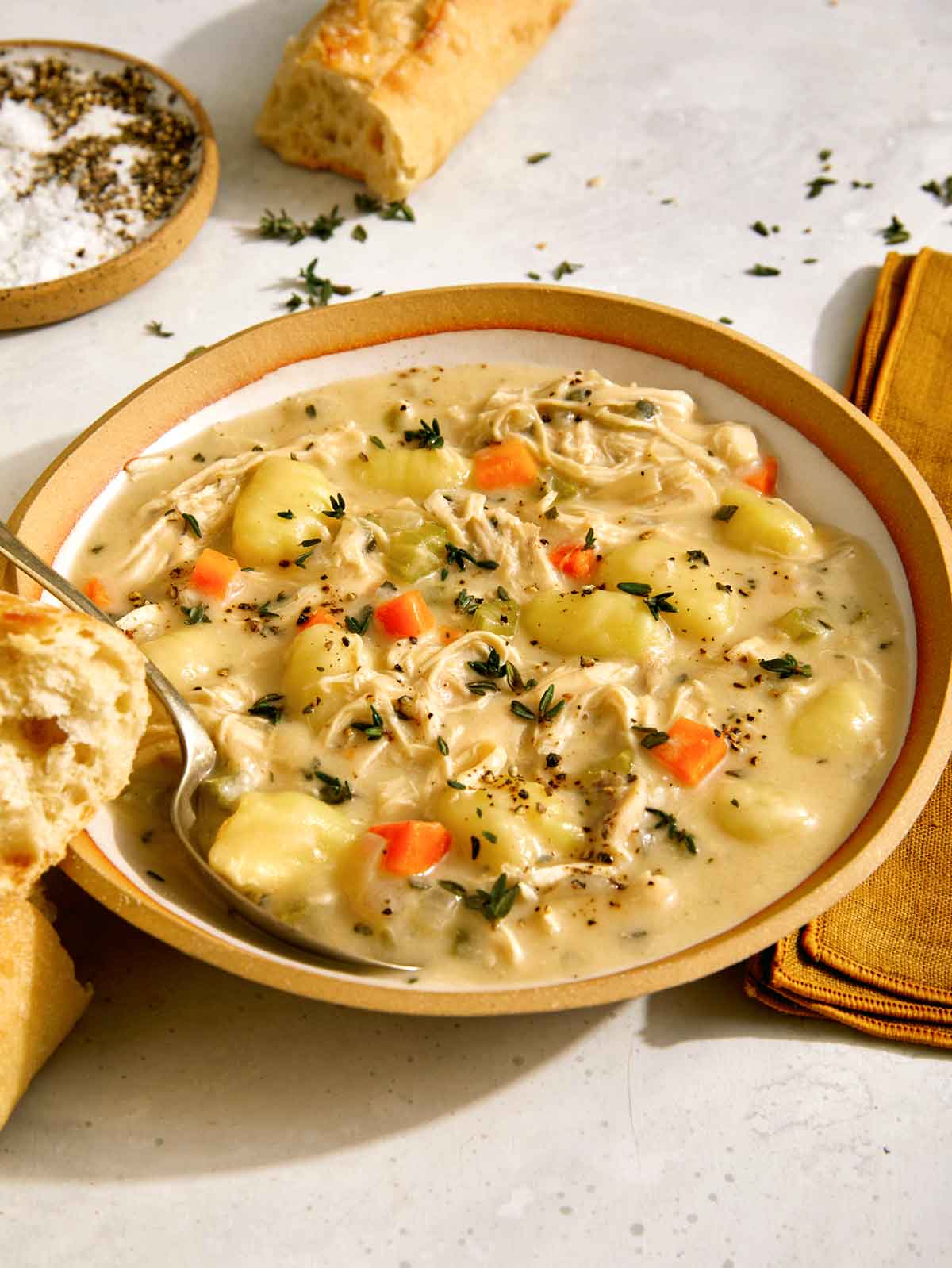 Chicken and gnocchi in a bowl with bread.