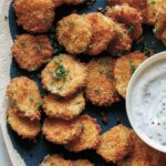 Fried pickle chips on a platter with ranch dressing.