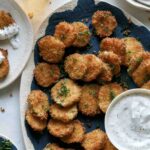 Fried pickle chips on a platter with beer on the side.