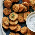 Fried pickle chips on a platter with ranch dressing.