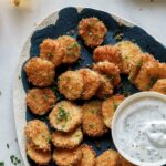 Fried pickle chips on a platter with beer on the side.