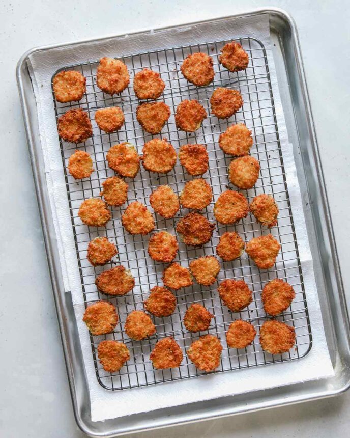 Fried pickle chips on a baking sheet.