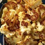 Roasted cauliflower recipe in a bowl with a spoon in it.
