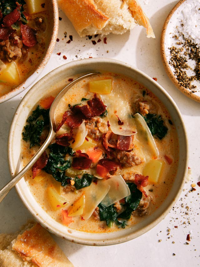 Zuppa toscana in two bowls with bread on the side.