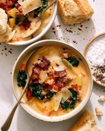 Zuppa toscana in two bowls with bread on the side.