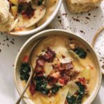 Zuppa toscana in two bowls with bread on the side.