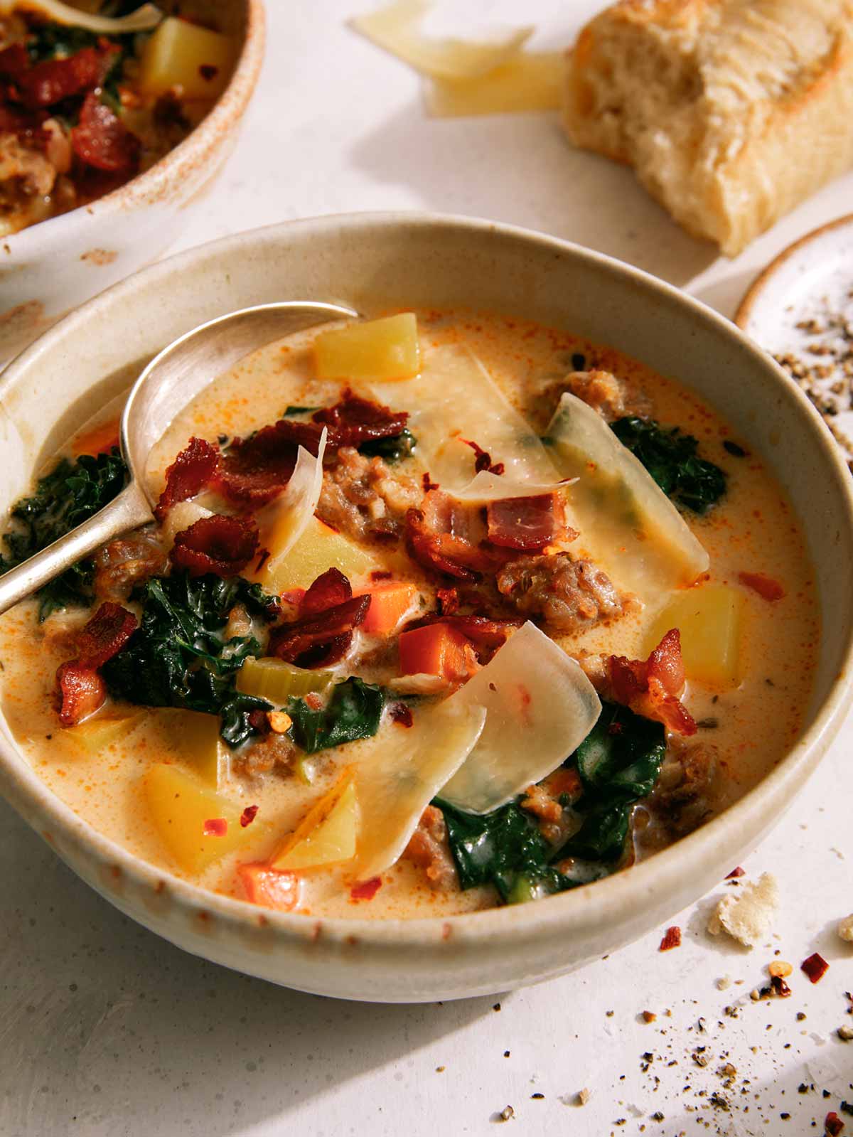 Zuppa Toscana in a bowl with bread in the background. 