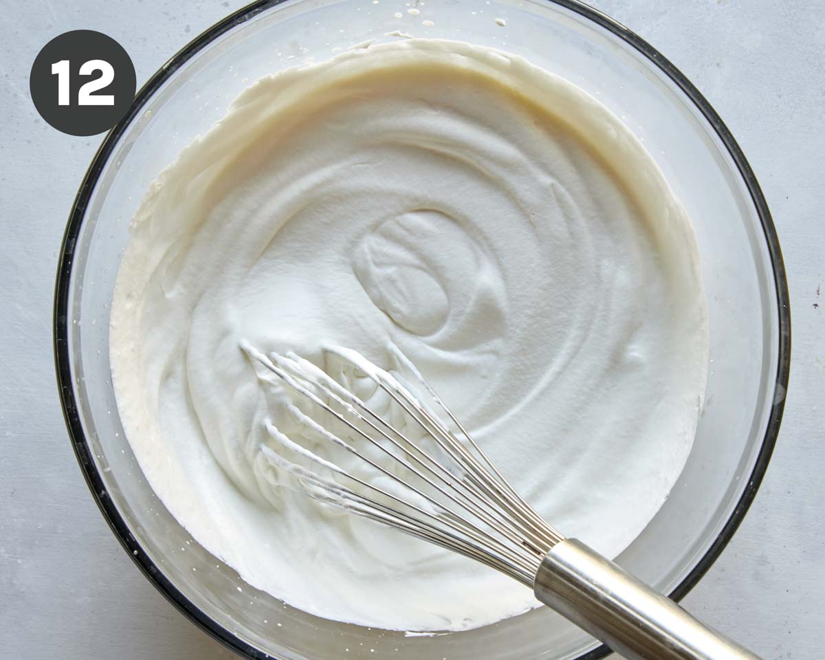 Whipped cream with stiff peaks in a bowl.