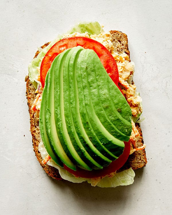 Chickpea salad sandwich with avocado on top.