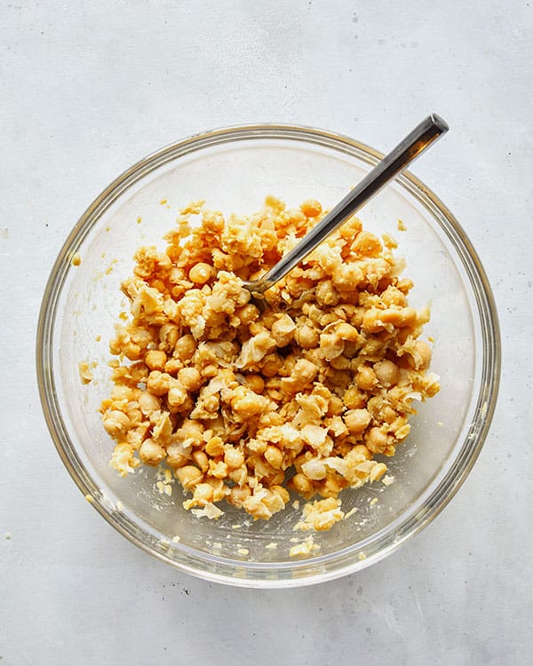 Chickpeas in a bowl mashed together.