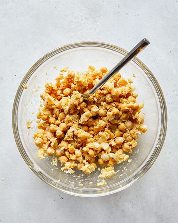 Chickpeas in a bowl mashed together. 