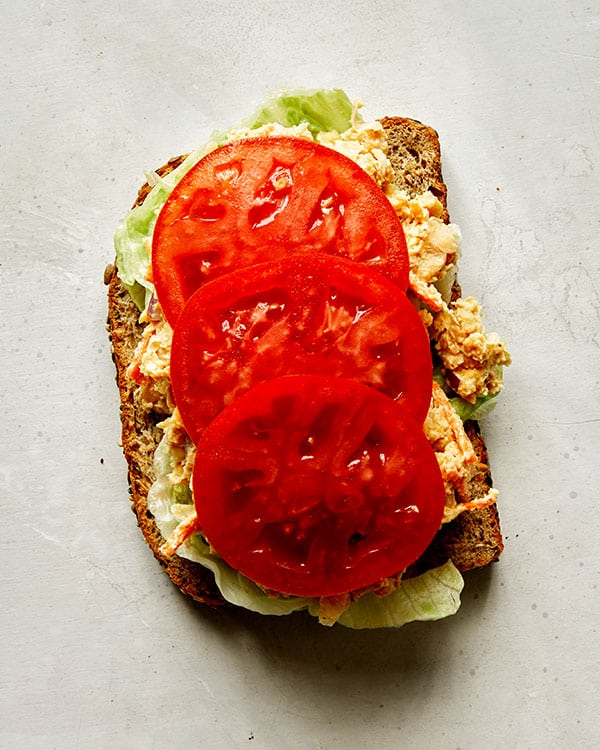 Chickpea salad sandwich with tomatoes on top. 