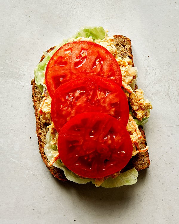 Chickpea salad sandwich with tomatoes on top.