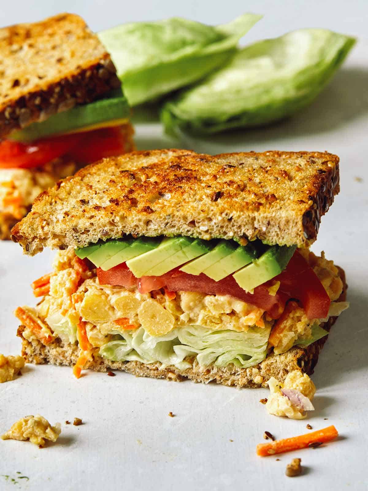 A chickpea salad sandwich cut in half on a surface. 