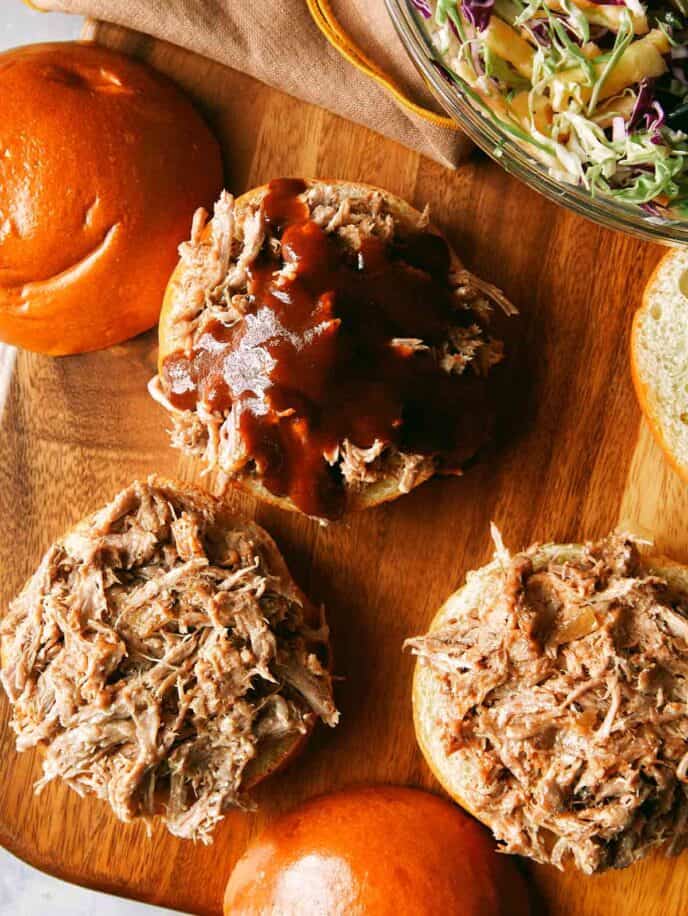 Pickled pulled pork sandwiches on a cutting board. 
