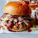 Pickled pulled pork sandwiches on a surface.