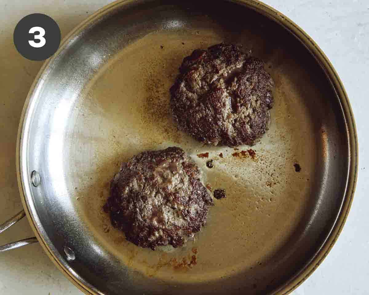 Hamburger patties being cooked in a skillet. 