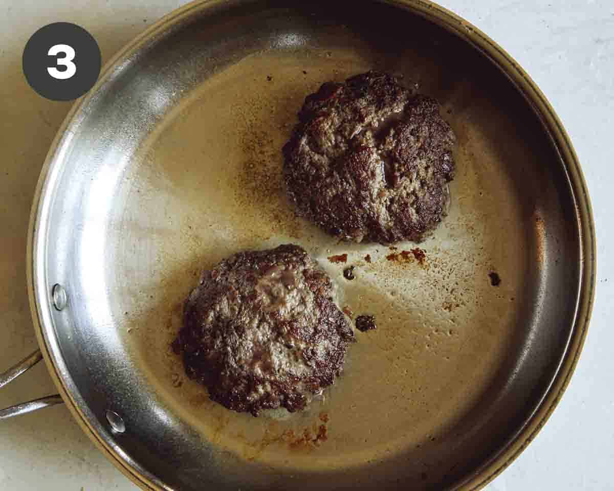 Hamburger patties being cooked in a skillet.