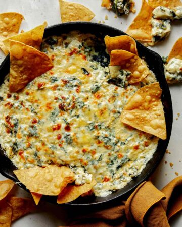 Spinach and artichoke dip in a skillet with chips on the side.