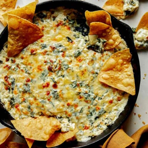 Spinach and artichoke dip in a skillet with chips on the side.