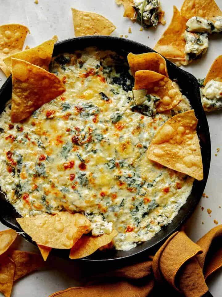 Spinach and artichoke dip in a skillet with chips on the side.