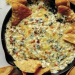 Spinach and artichoke dip in a skillet with chips on the side.