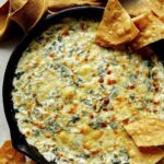 Spinach and artichoke dip in a skillet with chips on the side.