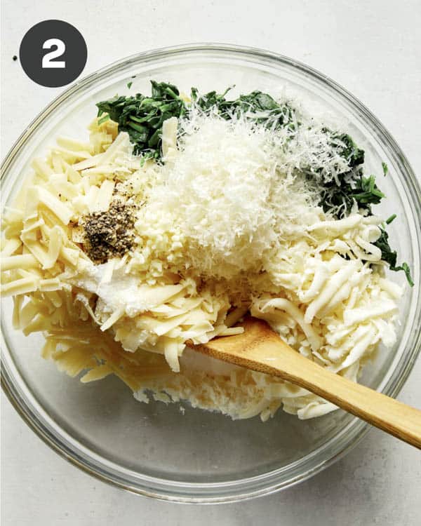 Spinach and artichoke dip mixing together in a bowl.