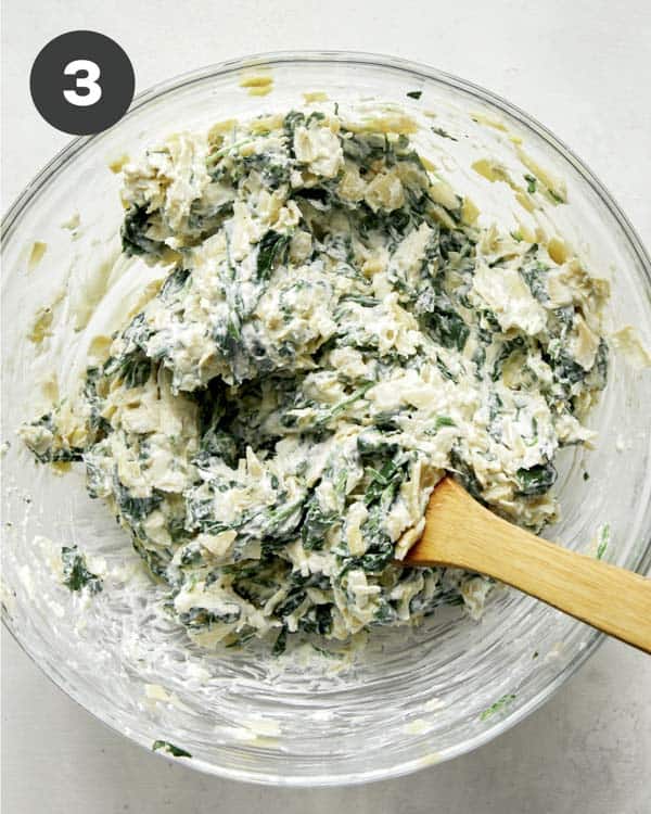 Spinach and artichoke dip filling in a bowl mixed together. 