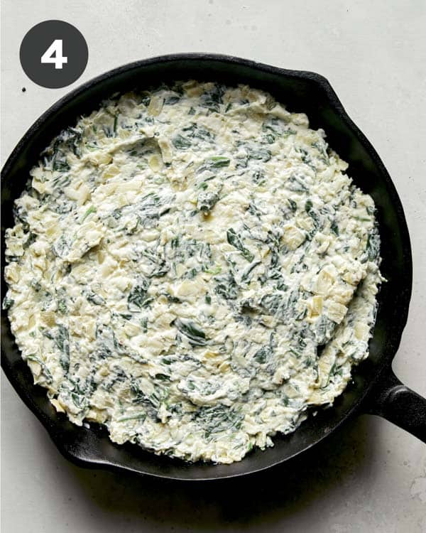 Spinach and artichoke dip in a skillet being ready to get baked. 