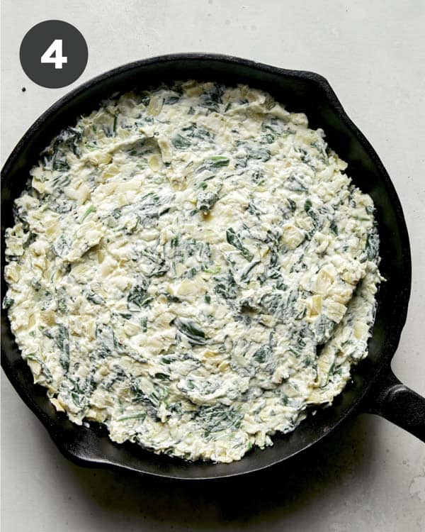 Spinach and artichoke dip in a skillet being ready to get baked.