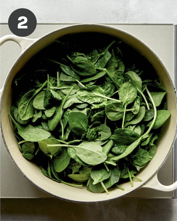Spinach in a pot with simmering water to make wilted spinach.