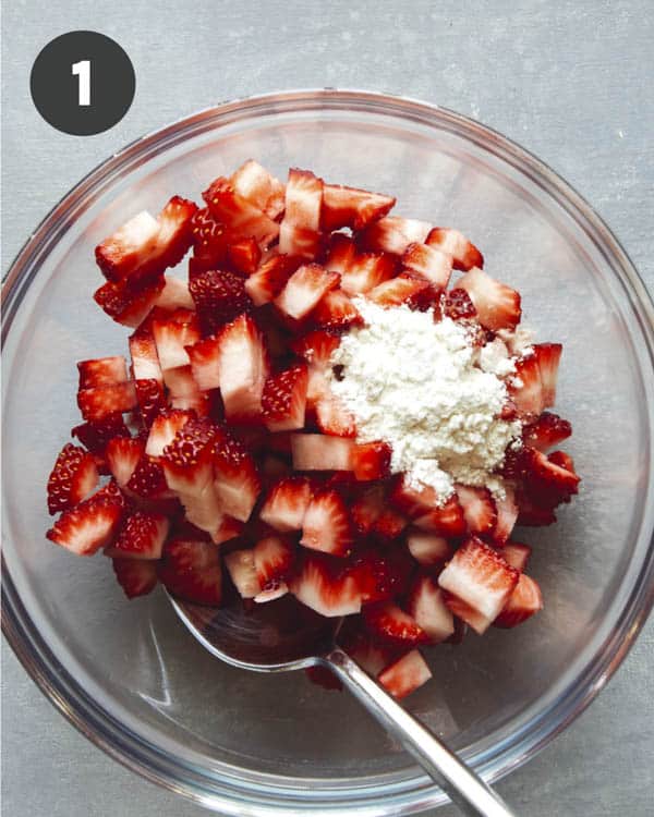 Strawberries in a mixing bowl with flour to make strawberry muffins.