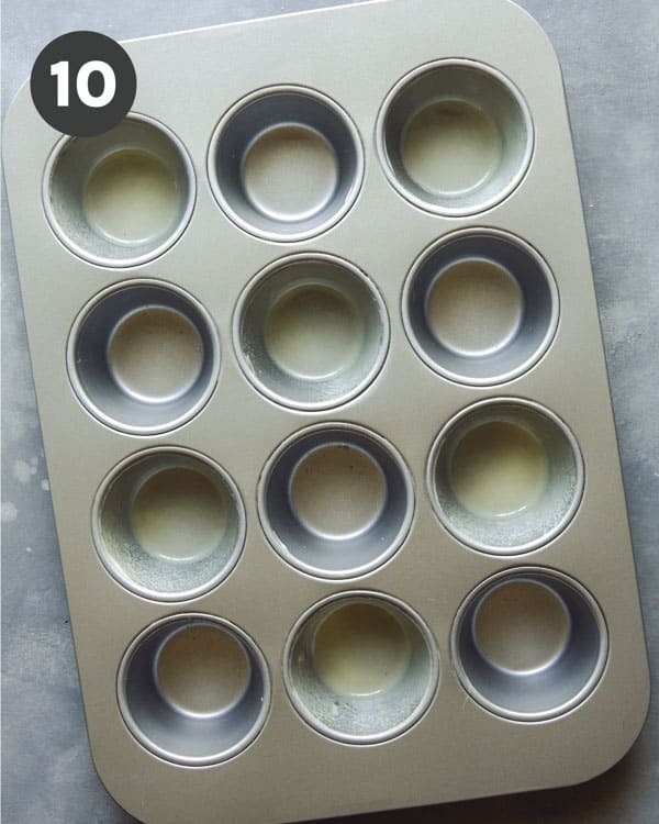 A muffin tin with some cavaties sprayed with cooking oil.