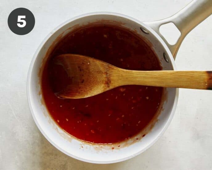 Sweet chili sauce in a pot with a wooden spoon.