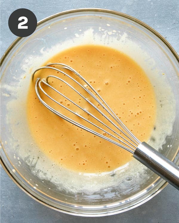 Caesar salad recipe in a bowl being whisked together. 