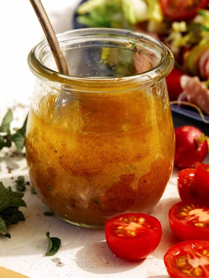 Red wine vinaigrette in a jar with tomatoes on the side.