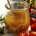 Red wine vinaigrette in a jar with a salad on the side.