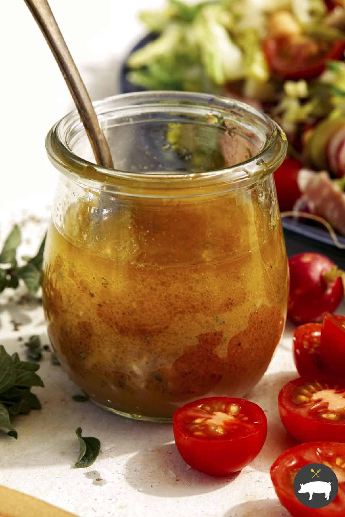 Red wine vinaigrette in a jar with a salad on the side.