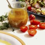 Red wine vinaigrette in a jar with a salad on the side.