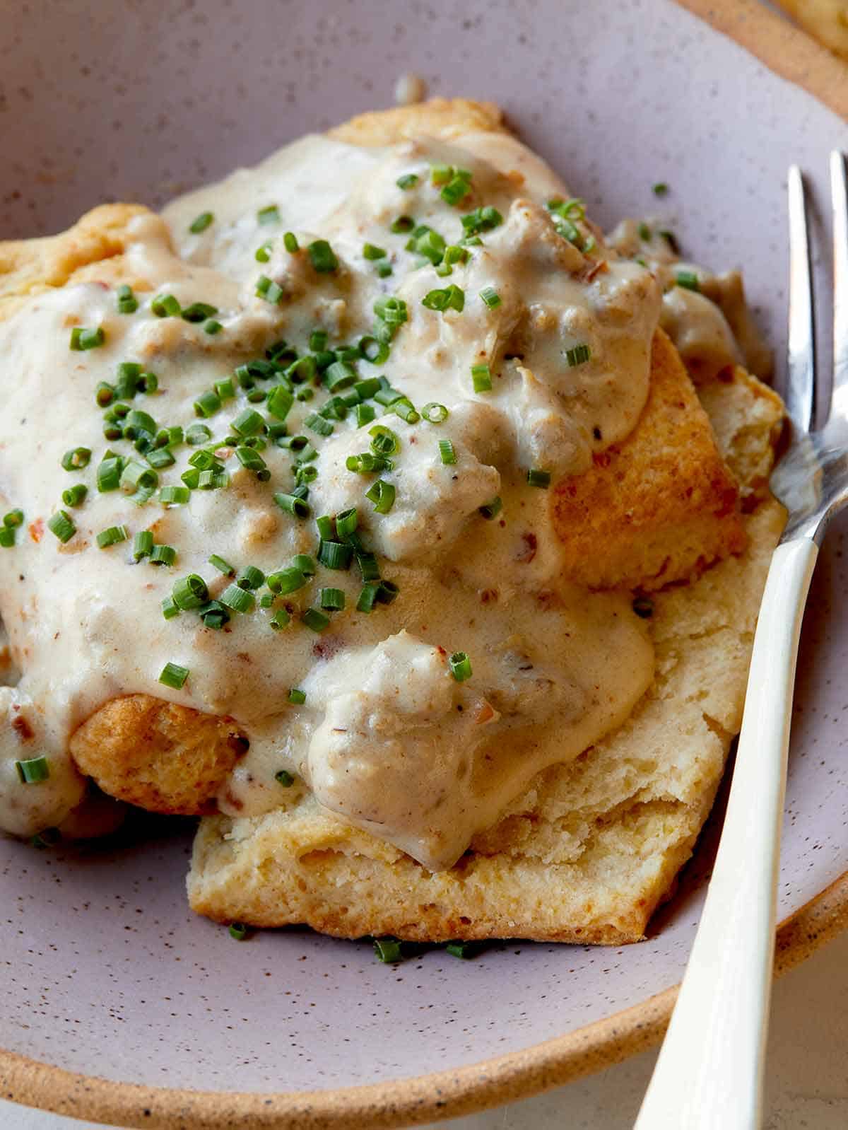 Biscuits and gravy in a bowl with a fork on the side. 