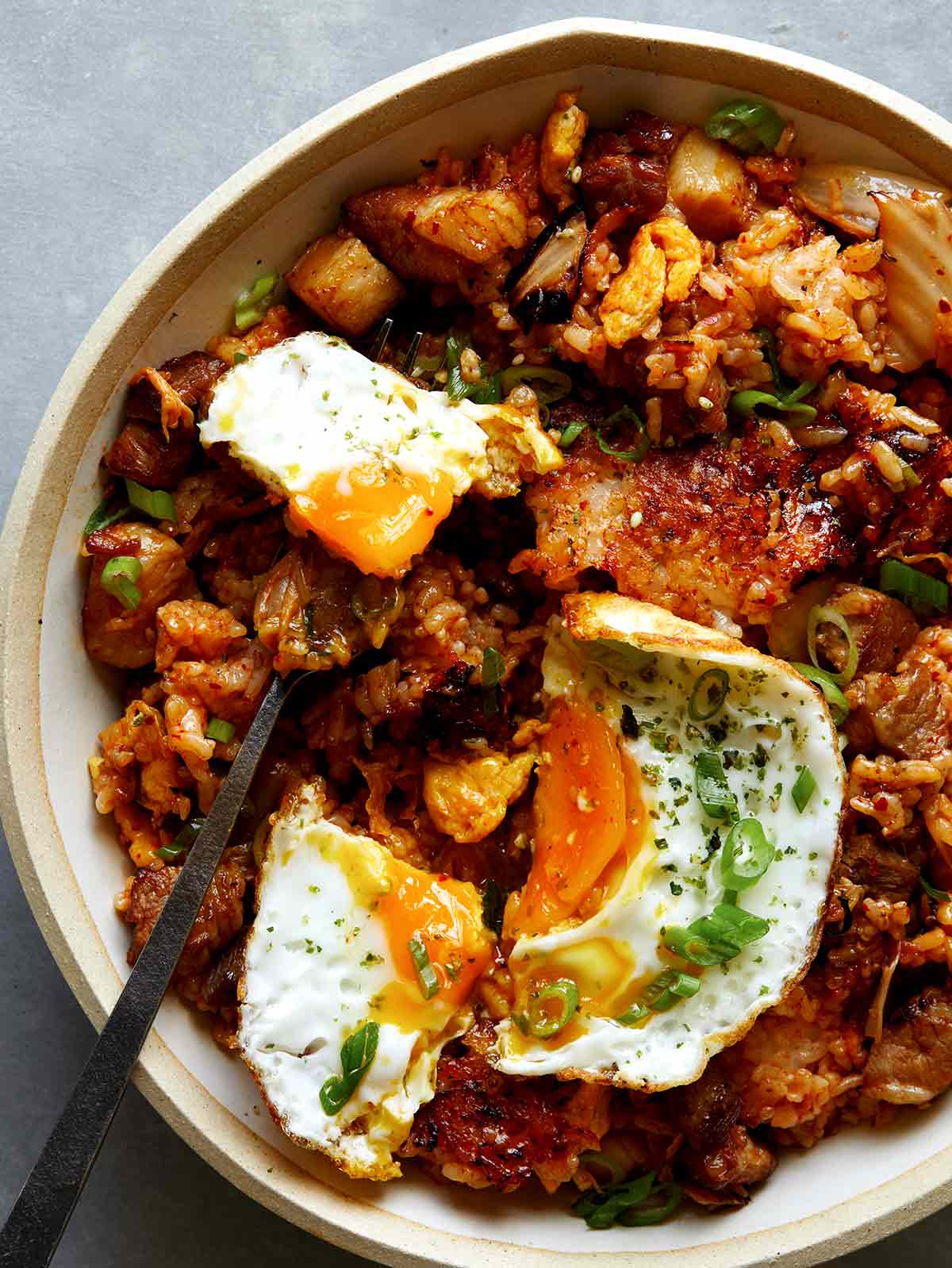 Kimchi fried rice being eaten with a fried egg on top. 